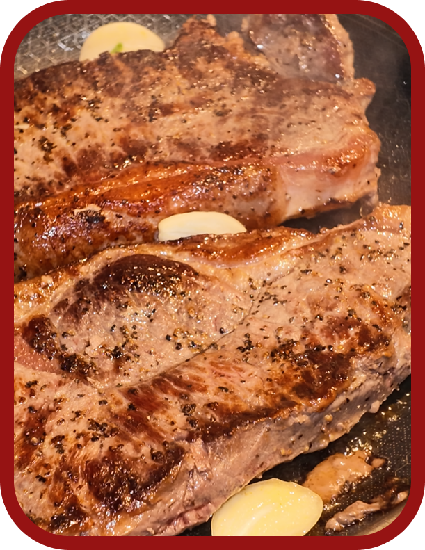 cooking-new-york-strip-steak Pan-searing Nutrafarms New York strip steaks with butter and garlic in a hot skillet.